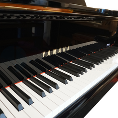 Yamaha G1E keyboard close-up, gold Yamaha logo on fallboard above black and white keys